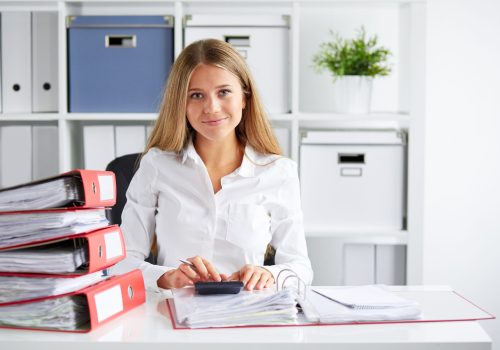 Smiling,Business,Woman,Calculates,Tax,At,Desk,In,Office